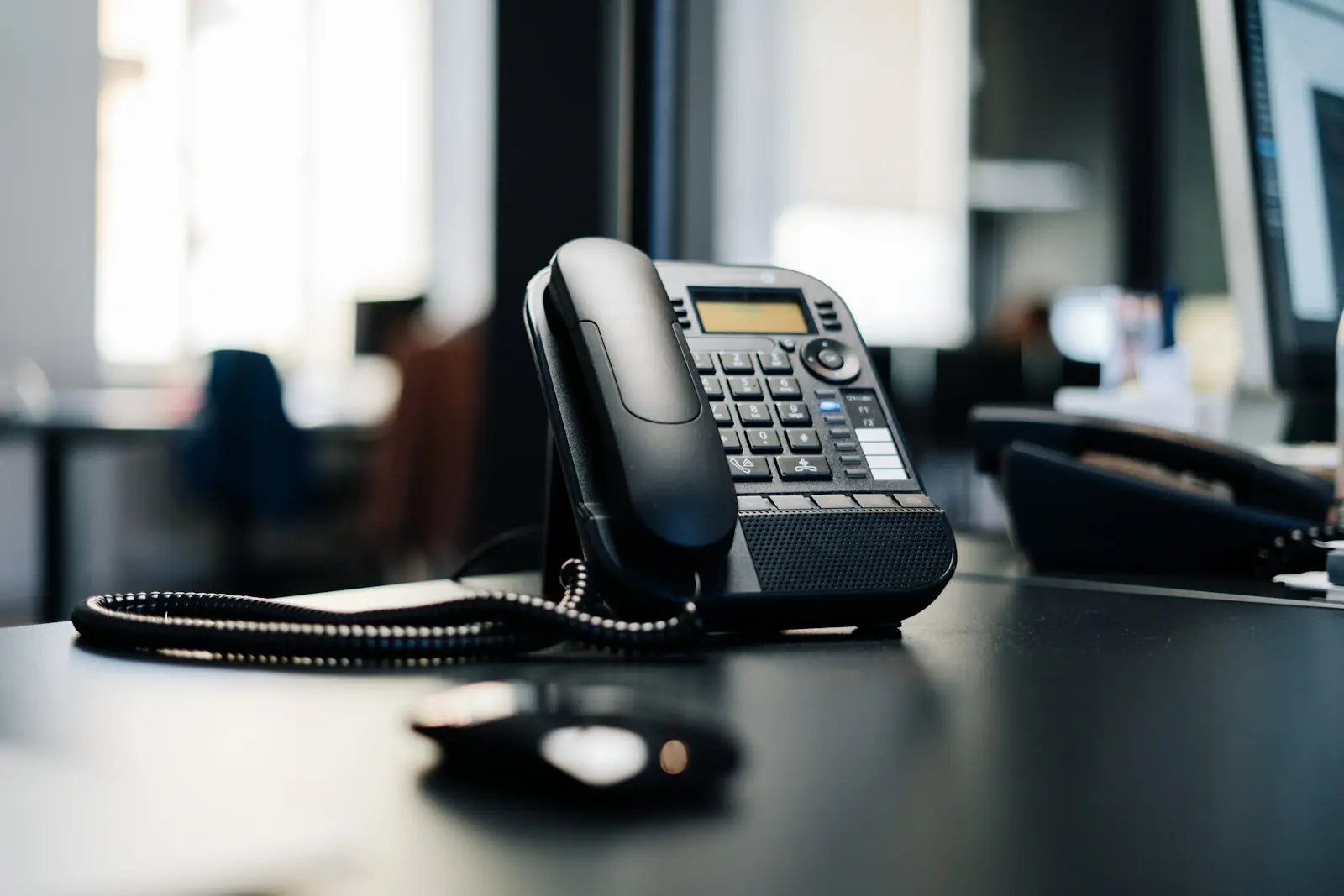 A desk phone on a dark desk