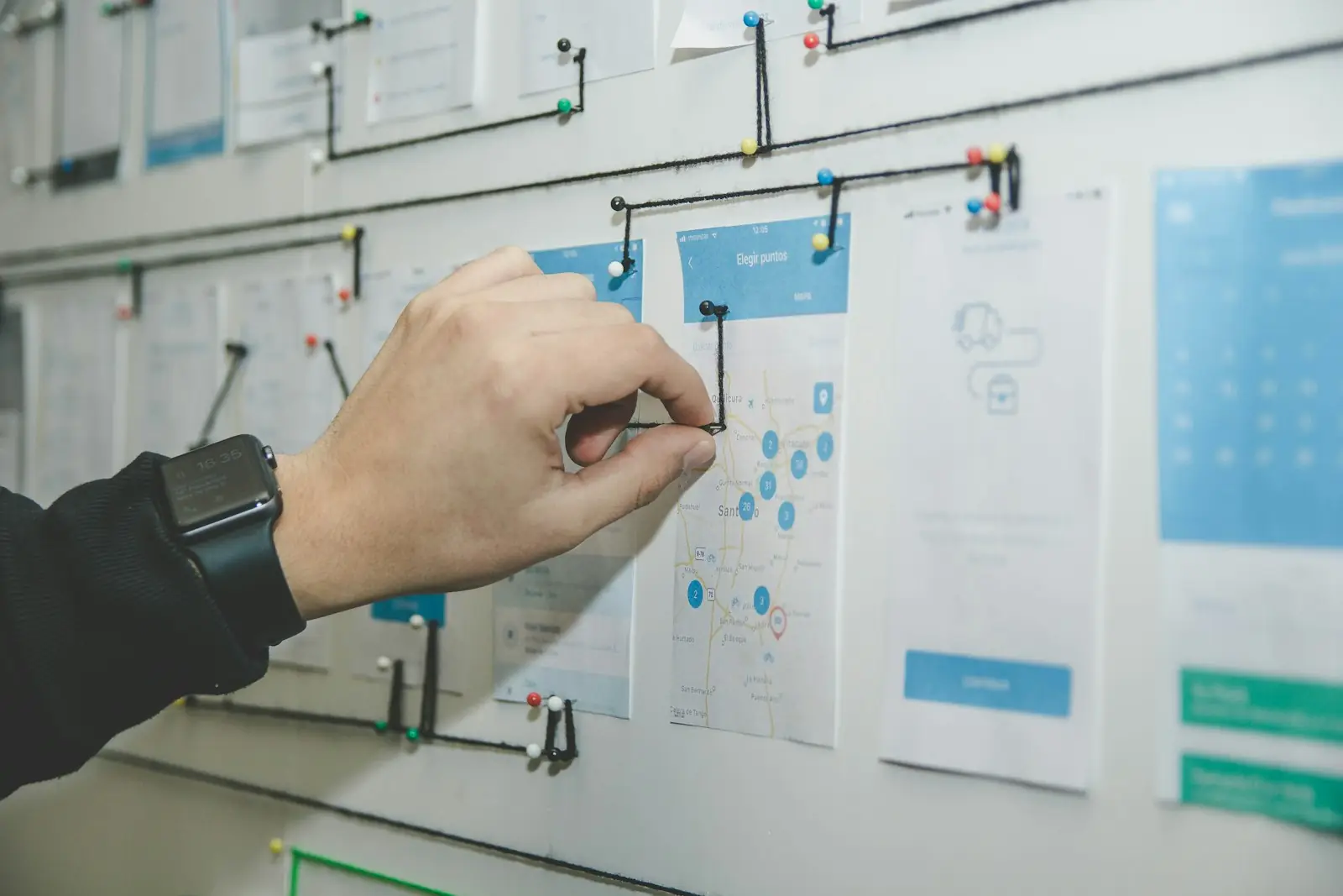 A hand pinning a process diagram to a wall